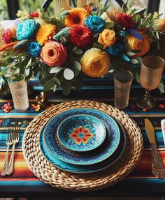 the table is set with colorful flowers and plates