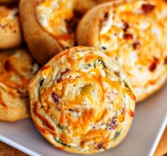 several small muffins with cheese and other toppings on a white platter