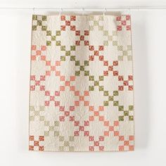 a quilt hanging on a clothes line with an orange and green checkerboard pattern