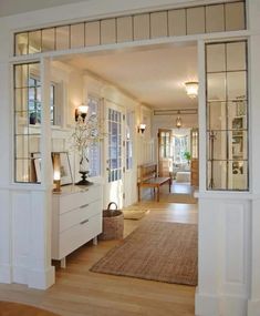 an open door leading to a living room with white furniture and wood flooring on either side