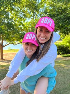 two girls wearing pink hats on their heads and one is holding onto the back of another girl