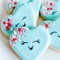 heart shaped cookies decorated with icing and sprinkles on a white surface