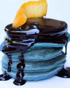 a stack of pancakes with chocolate syrup and an orange slice sitting on top of them