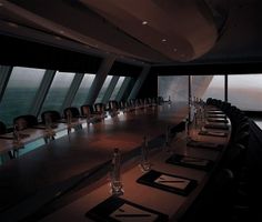 a long table is set up in front of large windows overlooking the water and sky