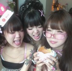 three young women posing for the camera while holding food