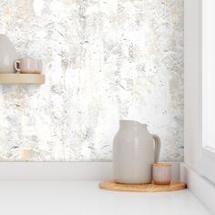 a white vase sitting on top of a counter next to a cup and saucer