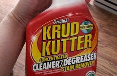 a hand holding a bottle of krud kutter cleaner on top of a wooden floor