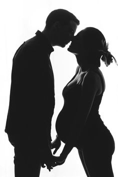 a man and woman kissing in silhouette against a white background