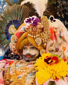 a close up of a person wearing a costume with flowers in front of him and a peacock on his head