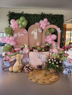 a table topped with lots of balloons next to a giant number one sign and other decorations