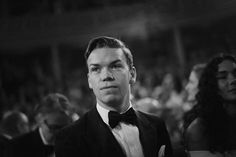 a black and white photo of a man in a tuxedo at an event