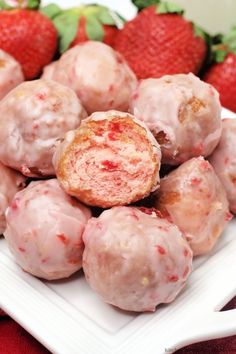 a white plate topped with donuts covered in frosting and strawberries next to each other