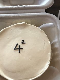 a cake with the number four on it in a plastic container, ready to be eaten