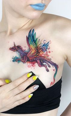 a woman's chest with a colorful tattoo on her left shoulder and the top half of her body covered in watercolor paint