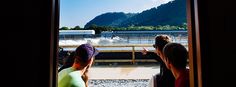 three people are looking out the window at a boat dock and mountains in the distance