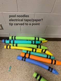 there are many different colored markers next to each other on the floor near a sign that says pool noodles electrical tape / paper tip carved to a point