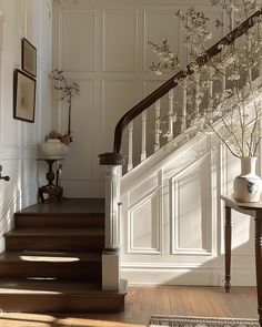 the stairs are lined with white flowers and framed pictures