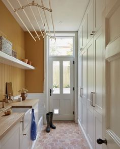 a hallway with white cabinets and brown tile flooring next to an open front door