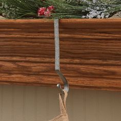 a metal hook hanging from the side of a wooden shelf next to a pine tree