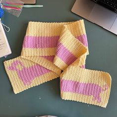 a knitted scarf sitting on top of a table next to a laptop