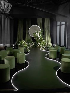 a room filled with lots of green chairs and tables covered in white flowers on top of them