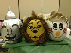 three pumpkins with faces painted on them are sitting on a green cloth covered table