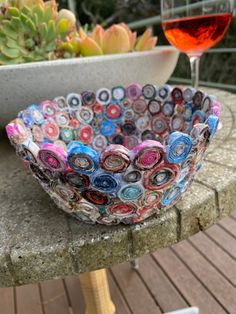 a bowl sitting on top of a cement table next to a glass of red wine