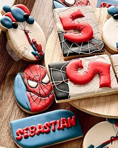 decorated cookies with the word spiderman are on a wooden table next to other cookies