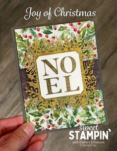 someone holding up a christmas card with the word noel on it and holly wreaths