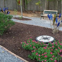 a garden area with flowers and benches in the back yard, surrounded by graveled walkways