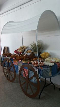 a table covered with lots of pastries and desserts next to a white tent