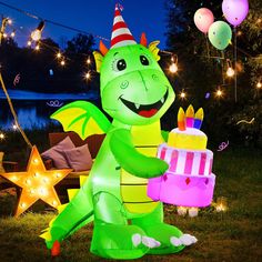 an inflatable dragon holding a birthday cake with balloons and lights on the background