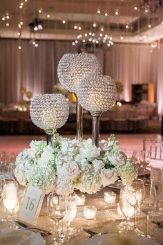 the centerpieces are surrounded by crystal vases and white flowers, along with candles