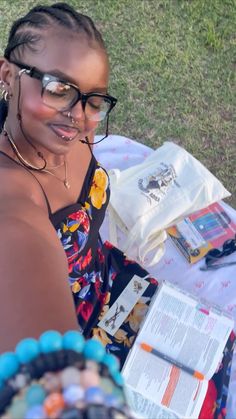 a woman sitting at a table with a book and cell phone in her hand while wearing glasses