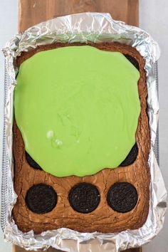 a cake with green frosting and oreo cookies in it on top of tin foil