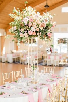 an elegant wedding reception with pink and white flowers in tall centerpieces on tables