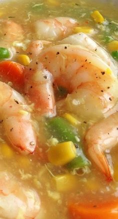 a bowl of soup with shrimp, corn and carrots