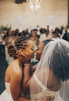 two brides embracing each other in front of a crowd