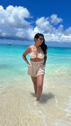 a woman is standing in the water at the beach with her hands on her hips