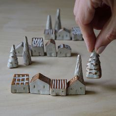 a hand is picking up some tiny houses