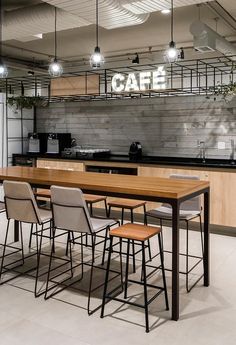 an industrial style kitchen with bar stools and wooden table in the center, surrounded by hanging lights