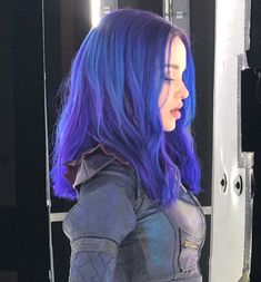 a woman with blue hair standing in front of a mirror