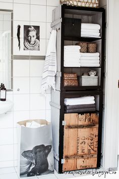 a bathroom with white tile and black shelving unit filled with linens, towels and other items