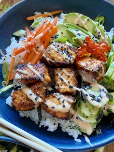 a blue plate topped with meat and vegetables next to chopsticks on top of rice