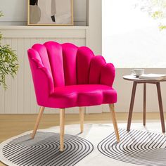 a pink chair sitting on top of a white rug next to a table and potted plant