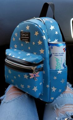 a blue backpack with white stars on it and a can of soda in the back pocket