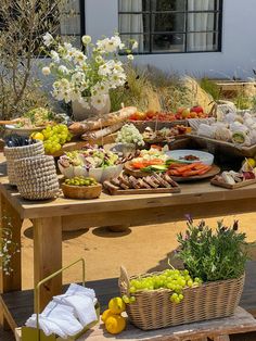 a wooden table topped with lots of different types of fruits and vegetables next to a building