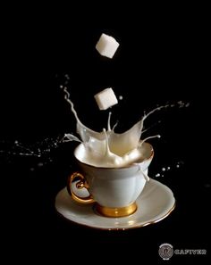 a cup filled with milk splashing out of it on top of a saucer