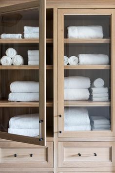 towels are stacked on top of each other in a wooden display case with glass doors