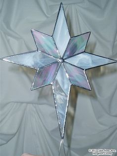 a glass snowflake ornament is shown on a white sheeted background